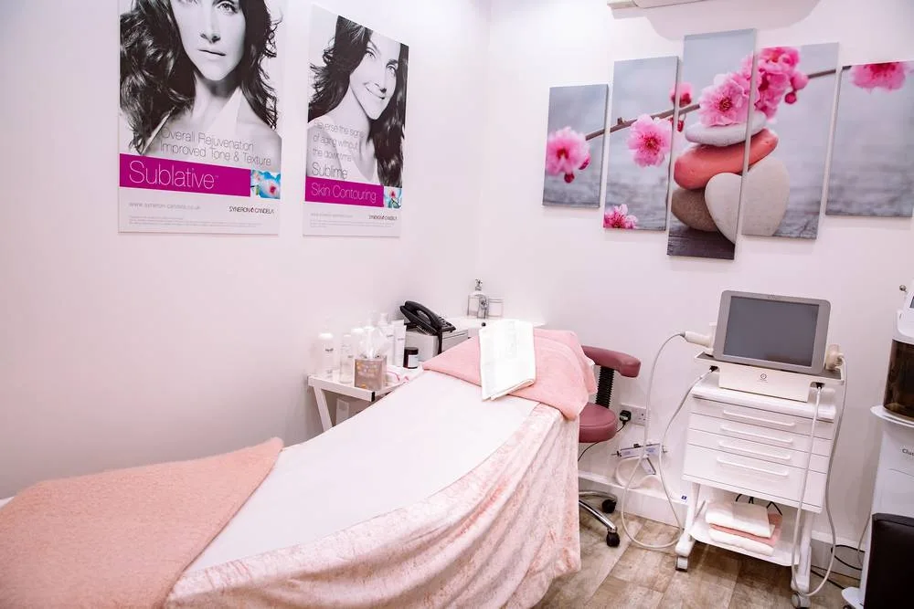 Aesthetics treatment room with a pink-draped couch and skin treatment equipment