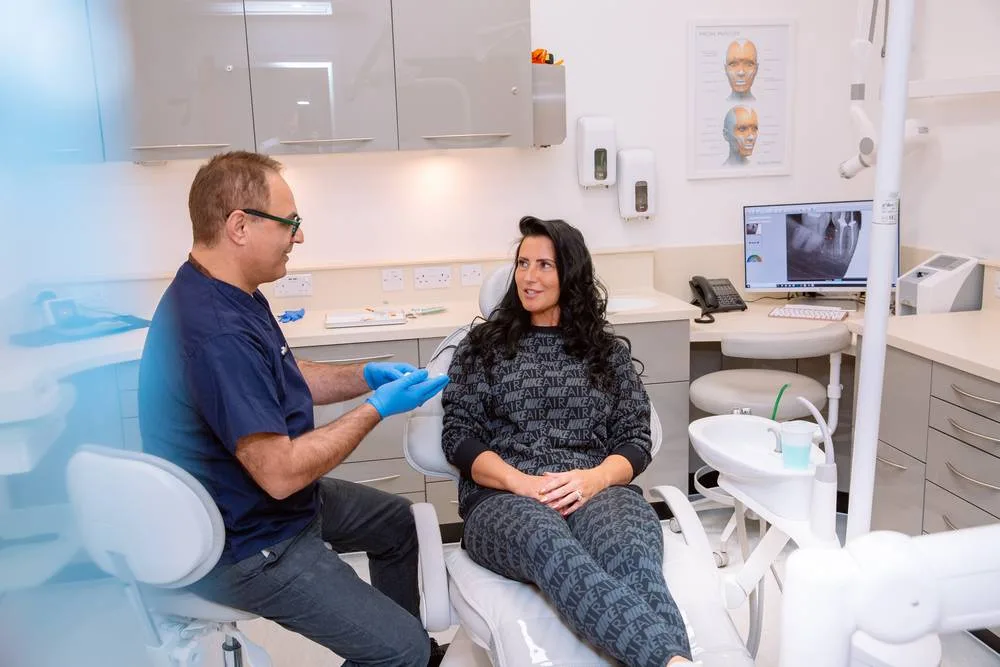 Dentist sitting chairside, talking a patient through her treatment