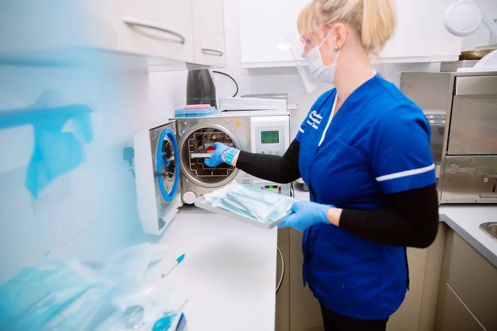 Dental nurse loading instruments into the autoclave