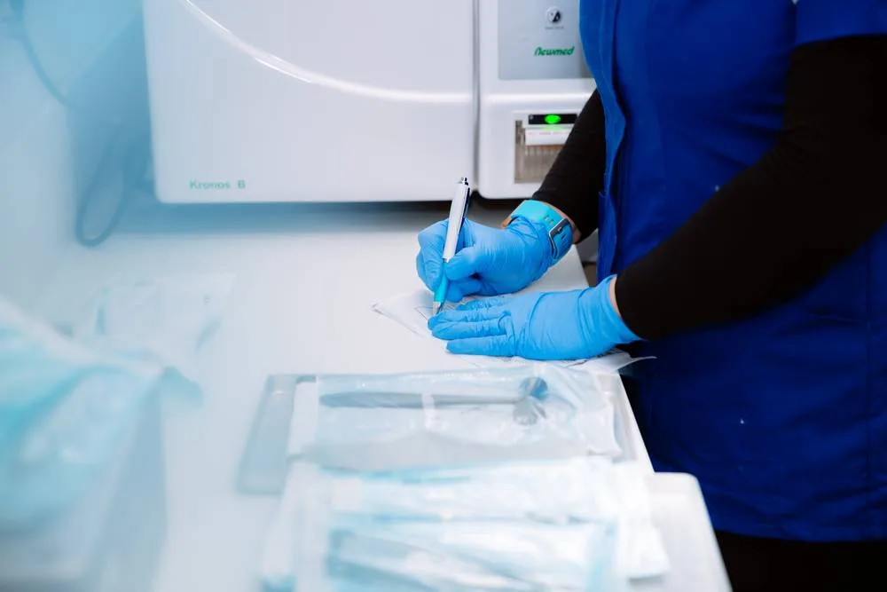 Dental nurse in gloves labelling sterilised instrument pouches