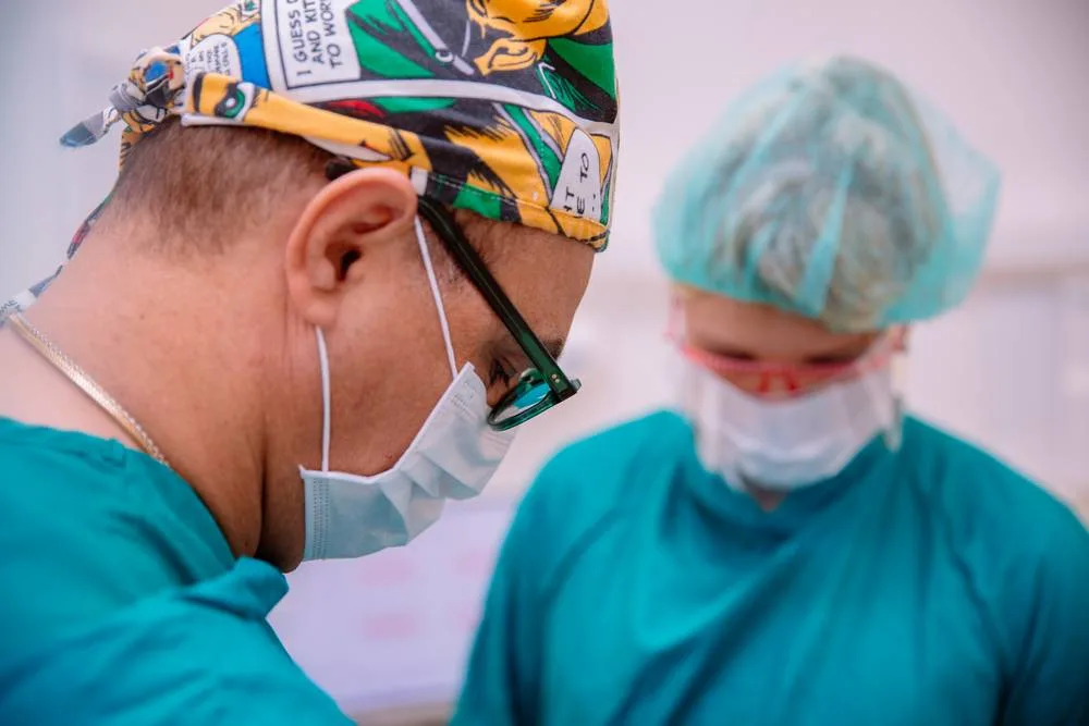 Close view of the dentist and dental nurse in caps and masks during a procedure