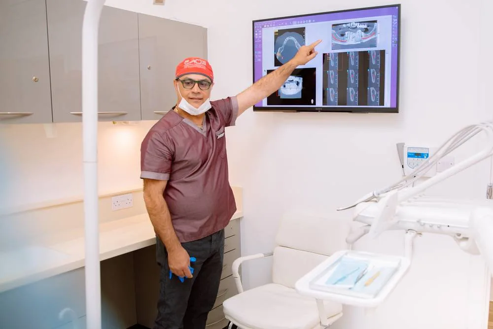 Dr Edvin in scrubs pointing to a 3D CBCT scan on the surgery screen