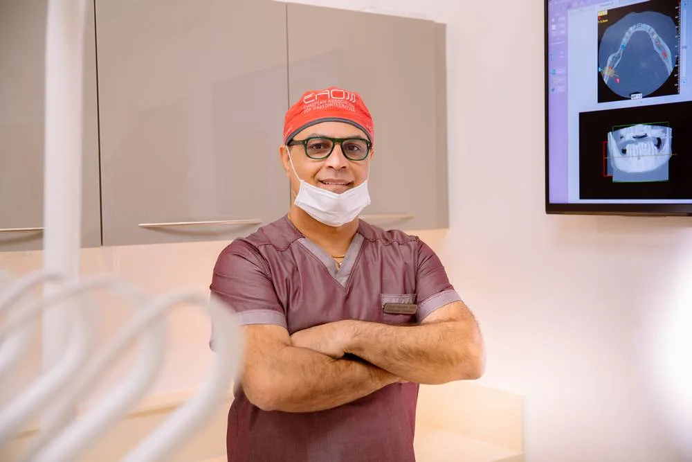 Dr Edvin, dentist at Enhance Dental Surgery, standing arms folded in the surgery