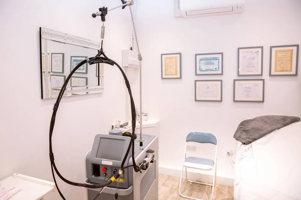 Laser treatment room with the hair removal laser and framed certificates on the wall
