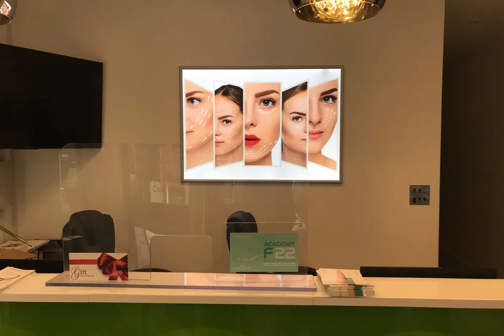 Reception counter with a large framed beauty photograph on the wall behind